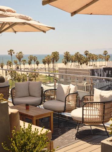 a patio with chairs and tables and the beach at Hotel Erwin Venice Beach in Los Angeles