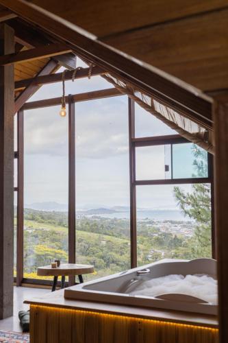 a bath tub in a room with a large window at Chalés do Tabuleiro, Chalé 1 in Palhoça