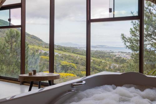 a bath tub in a room with windows at Chalés do Tabuleiro, Chalé 1 in Palhoça