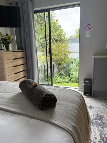 a towel on a bed in a bedroom with a window at Serenity Luxury Guesthouse in Krugersdorp