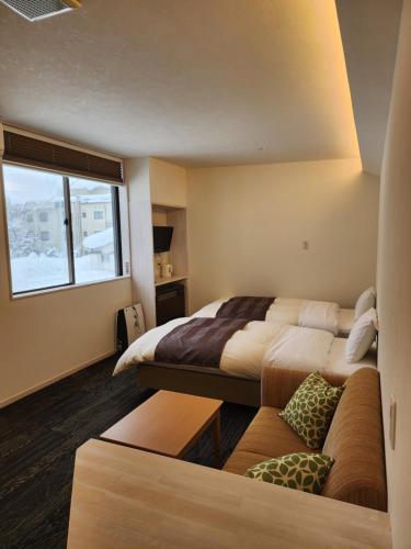 a hotel room with two beds and a couch at Hakuba Hotel Hana-no-Sato in Hakuba