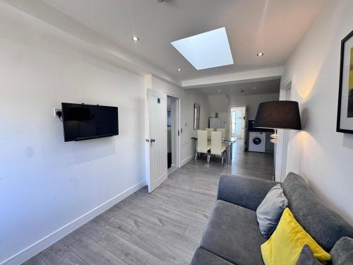 a living room with a couch and a television on a wall at OX London Heathrow stay - 1 BUS to HEATHROW in New Bedfont