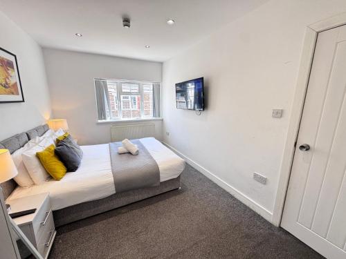 a bedroom with a bed with yellow pillows and a window at OX London Heathrow stay - 1 BUS to HEATHROW in New Bedfont