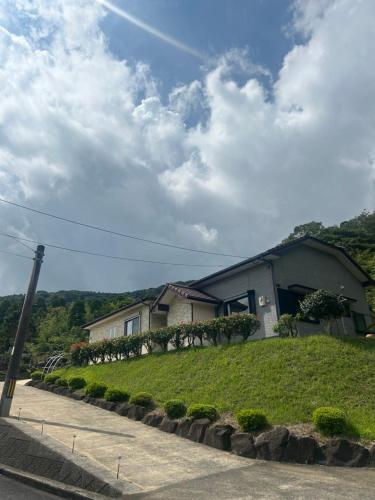 una casa al lado de una colina con una calle en アットホーム五島, en Goto