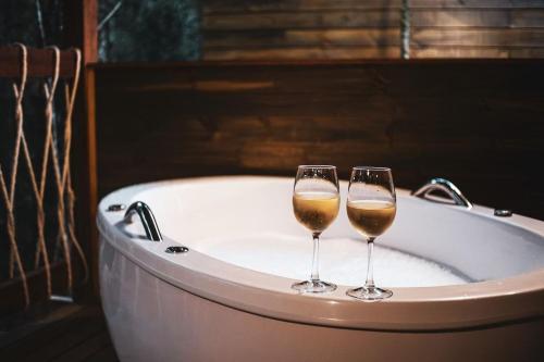 two wine glasses sitting on top of a bath tub at Pousada Chales da Mantiqueira - Campos do Jordão in Campos do Jordão