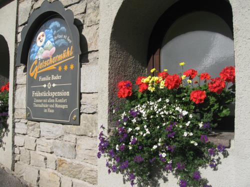 a sign for a restaurant with flowers in a window at Landhaus Gletschermühle in Bad Gastein