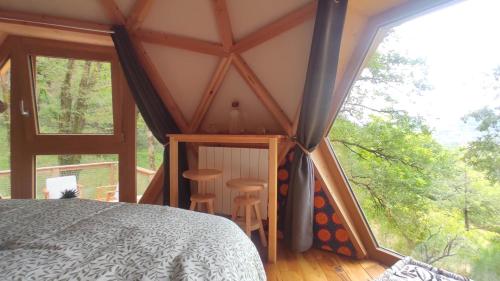 a bedroom with a bed and a large window at Gîte Insolite La Parenthèse Boisée Aveyron in Bouillac