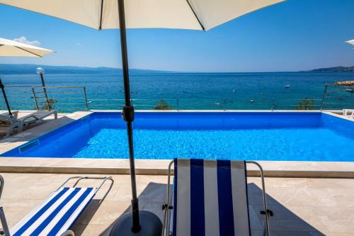 a swimming pool with an umbrella and two chairs and an umbrella at Villa Veronika in Omiš