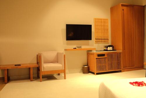 a room with a tv and a chair and a table at Red River Retreat in Hatikhuli