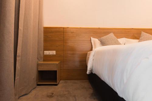 a bedroom with a white bed with a wooden headboard at Moro Kihaadhoo in Kihaadhoo