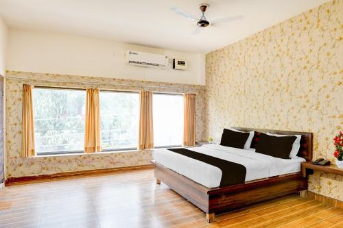 Un dormitorio con una cama grande en una habitación con ventanas. en Hotel O Raj Ambessy, en Rāmpura