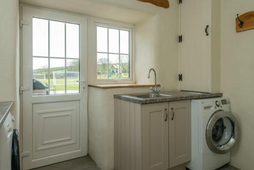 a kitchen with a sink and a washing machine at Deri-Sarn in Sarn