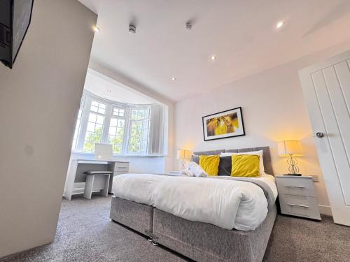 a bedroom with a large bed with yellow pillows at OX London Heathrow stay - 1 BUS to HEATHROW in New Bedfont