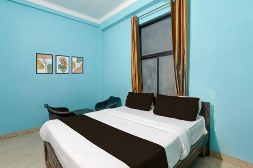 a bedroom with a bed with blue walls and a window at Hotel O Shivam International in Utrāhtia