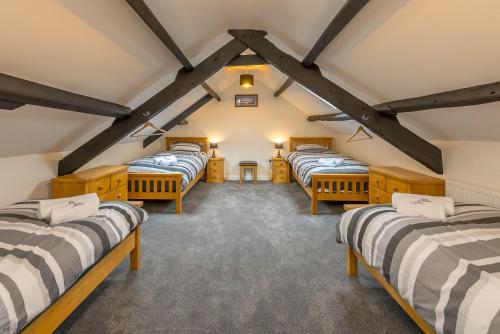 a row of four beds in a room with beams at Ty-Newydd-Llannor in Llannor