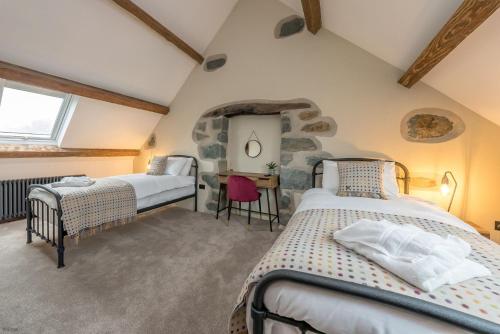 a bedroom with two beds and a stone wall at Hendre-Feinws in Pwllheli