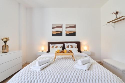 une chambre blanche avec un grand lit avec une table dessus dans l'établissement Le Cliquot - Maison - Spa - Jardin - Parking Gratuit, à Reims