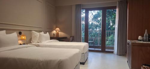 a hotel room with two beds and a balcony at Red River Retreat in Hatikhuli