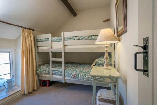 a bedroom with two bunk beds and a table with a lamp at Lloft-Sarn in Sarn