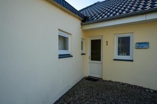 a white house with a white door and windows at Haus Sonnenwinkel Bungalow 1 in Dahme