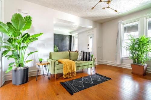 a living room with a green couch and two plants at Prime Location Top Rated Clean Parking Free! in Columbus