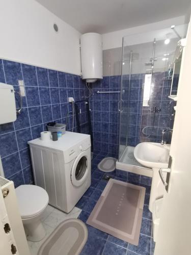 a bathroom with a toilet a sink and a washing machine at Apartman Meridian in Zaječar