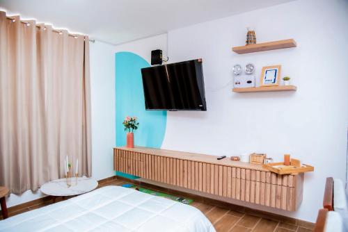 a bedroom with a bed and a tv on the wall at Hogar de Olas Huanchaco in Huanchaco