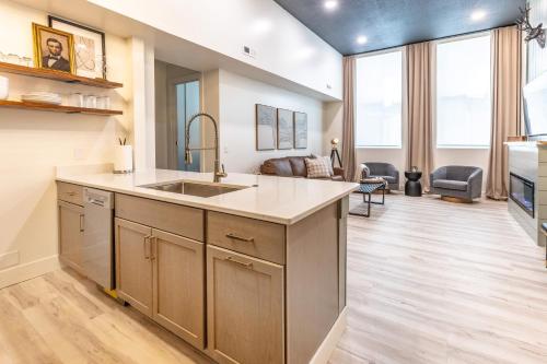a kitchen with a sink and a living room at Boutique 1BR Condo - Walk to Memorial Stadium - Historic Hayward Place in Lincoln
