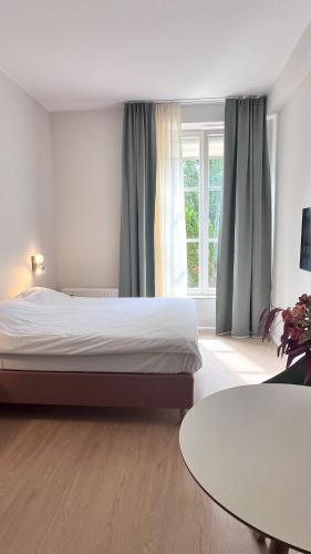 a bedroom with a bed and a table and a window at Key Inn Appart Hotel Belair in Luxembourg