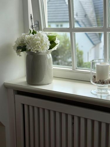 a vase with white flowers sitting on a window sill at Ocean-View-II-Holiday-Apartments-Sylt in Rantum