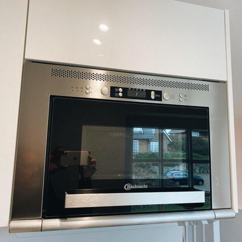 a microwave oven with a person taking a picture at Ocean-View-II-Holiday-Apartments-Sylt in Rantum