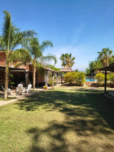 een tuin met twee stoelen en een huis met palmbomen bij las palmeras,Valle Viejo,Catamarca, dpto 1er piso in San Isidro