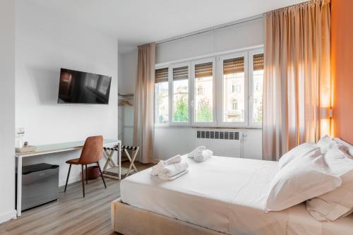 a bedroom with a white bed and a desk and window at Carducci Collection in Bologna