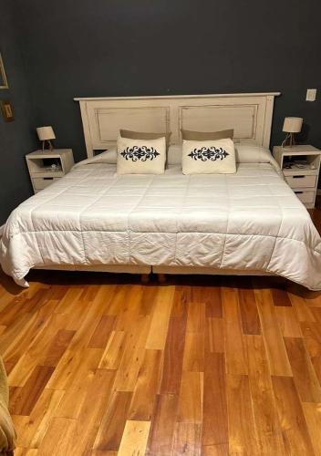 a bedroom with a bed with white sheets and wooden floors at Alquiler en Lobos, Empalme in Empalme Lobos