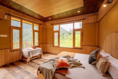 a bedroom with a large bed in a room with windows at Sneha Cottage, Tirthan Valley - #riverside #premium room #cafe #comfortable stay #garden with fireplace #property of the year in Jibhi