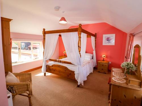 a bedroom with a canopy bed in a room at Coachman's Cottage in Henley