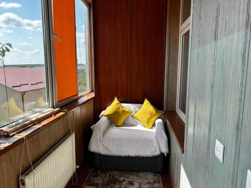 a small room with a bed with yellow pillows at Найкраща Квартира in Kamianets-Podilskyi