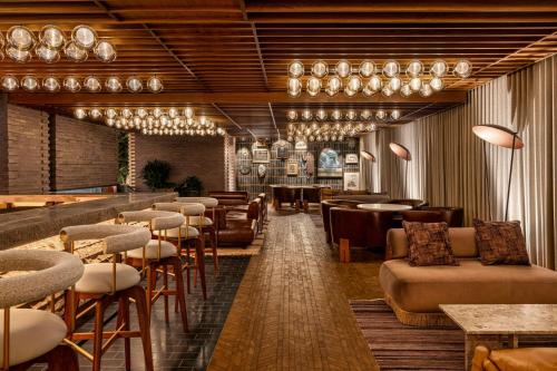 a restaurant with a bar with chairs and tables at The REMI Scottsdale, Autograph Collection in Scottsdale