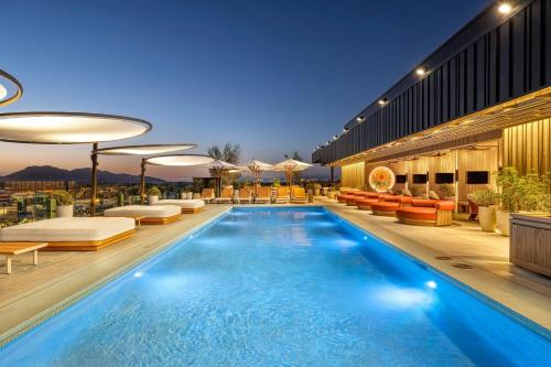 a swimming pool with chairs and a building at The REMI Scottsdale, Autograph Collection in Scottsdale
