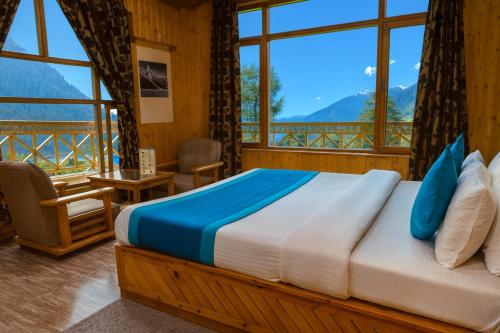 a bedroom with a bed with a view of mountains at Shree Ram Cottage, Manali - 1,2,3 Bedroom Luxury Cottages Available in Manāli
