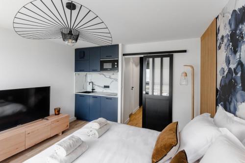 a bedroom with a large white bed and a television at Horizon bleu depuis un studio unique in Carnac