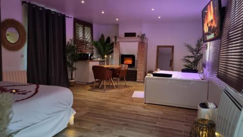 a bedroom with a bed and a table with a fireplace at Suite de charme avec JACUZZI illimité et jardin privatif in Saint-Prix