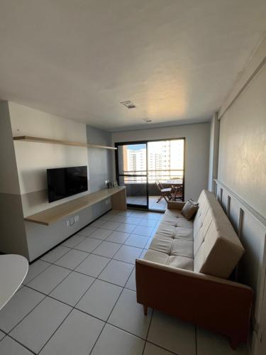Una sala de estar con un sofá y un televisor de pantalla plana. en Apt Vista Mar, en Fortaleza