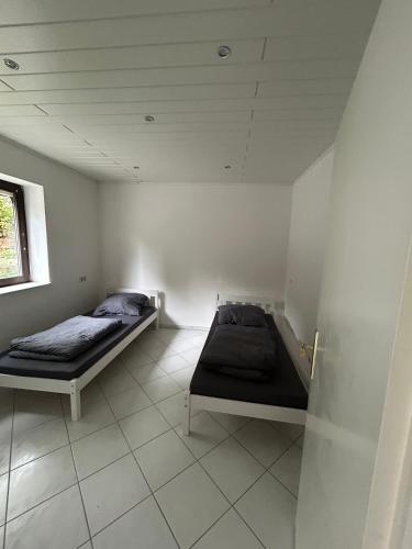two beds in a white room with a window at Wohlfühloase Hennef in Dambroich