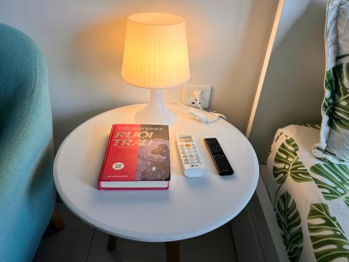 a table with a lamp and a book and a remote control at Vinhome Grand Park Homestay-HappyStay in Gò Công
