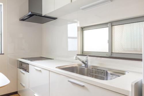 a white kitchen with a sink and a window at Nogata Station 3 minutes on foot , 15 minutes to Shinjuku in Tokyo