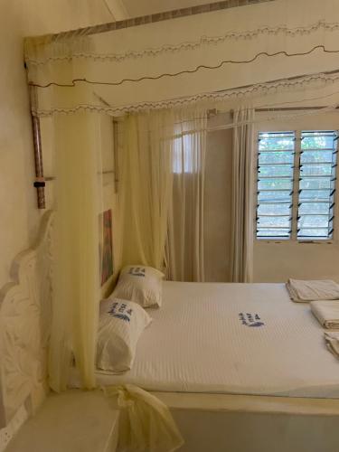 a bedroom with a white bed with a window at Watamu 2B in Watamu