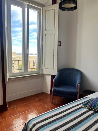 a bedroom with a bed and a chair and windows at Peniche Hostel in Peniche