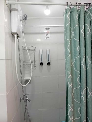 a shower with a green shower curtain in a bathroom at DaLei 3- 103 Sleeps 8pax at Marina Spatial Condominium in Dumaguete City in Dumaguete