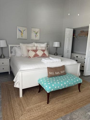 a bedroom with a large white bed and a bench at August Breeze - Beach, Fun, Sun, Close to Sights in St. Augustine